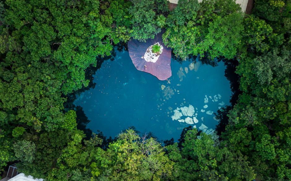 Vista aérea de un cenote de aguas azules rodeado de selva en Quintana Roo, sin personas