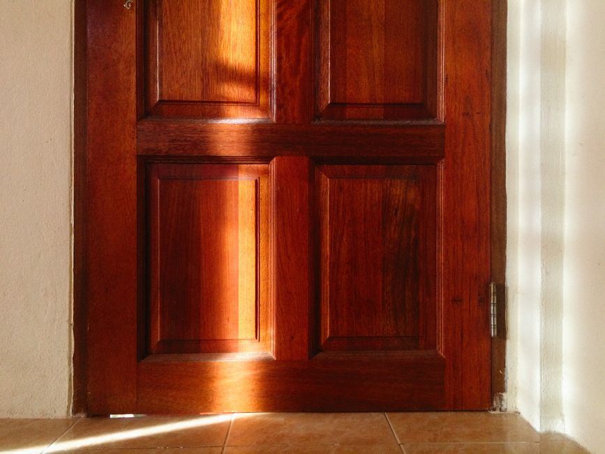Puerta de madera cerrada con paneles, iluminada por un rayo de luz cálida de tarde